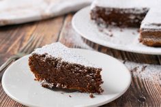 a piece of chocolate cake on a white plate with powdered sugar around the edges