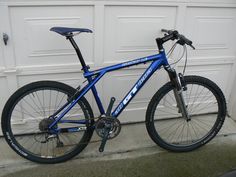 a blue mountain bike parked in front of a garage door