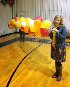 a woman is holding balloons in an indoor gym