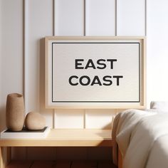 an east coast sign on a wall next to a small table with two vases