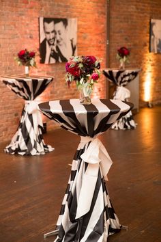 black and white striped table cloths with red flowers on them in front of brick wall