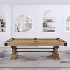 a pool table in the middle of a room with two windows and shelves on either side