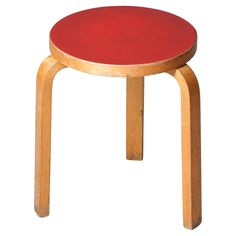 a small wooden stool with a red seat on the top and bottom, against a white background