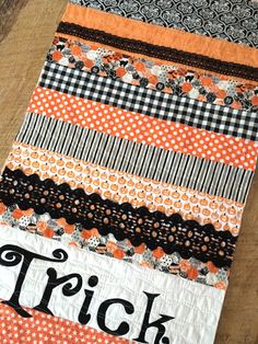 an orange and black quilt with the word trick written on it's center strip