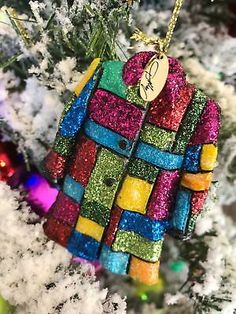 a christmas ornament hanging on a tree in the shape of a colorful jacket