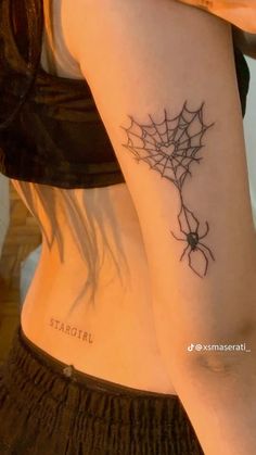 a woman with a spider web tattoo on her left arm and the word startii written in black ink