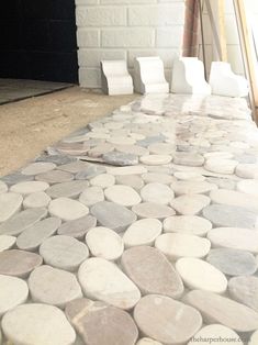 the floor is being laid out with white and gray stones on it, along with two chairs