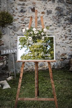 a sign with flowers on it in front of a stone wall that says, wedding ceremony