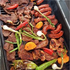 the grill has many different types of meat and vegetables cooking on it's side