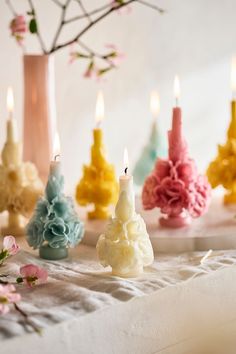 several candles with different colored flowers in front of one candle and the other on a table