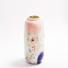 a pink and blue vase sitting on top of a white table