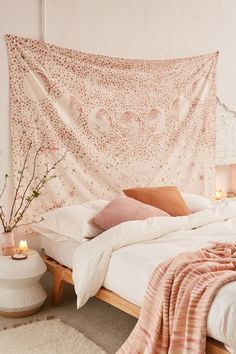 a bed with a pink blanket hanging over it's headboard and pillows on top of it