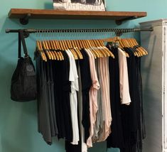 an open closet with clothes hanging on hangers and a handbag next to it