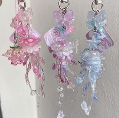 three key chains hanging from the side of a white wall with pink and blue flowers on them