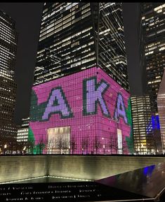 a large building with the letters ak on it's side in front of other tall buildings