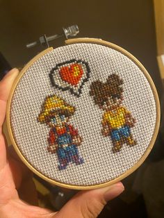 someone is holding up a cross - stitch embroidery kit with two people in the shape of a heart