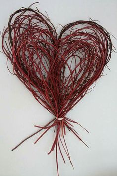 a heart shaped piece of red string on a white surface