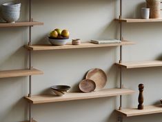 some shelves with bowls, plates and other items on them in a room that has white walls