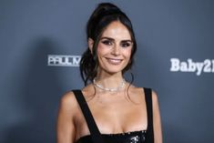 a woman in a black dress smiling at the camera and wearing a choker necklace