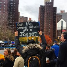 a person holding up a sign in the middle of a street with other people standing around