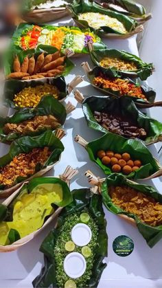 a table topped with lots of different types of food on leafy plates next to each other