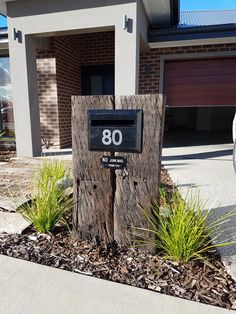 a house with a mailbox and number on the front door is next to a tree stump