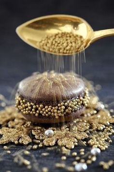 a golden spoon sprinkling seeds on top of a chocolate cake