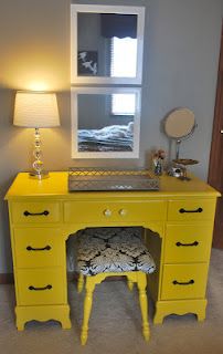 a yellow desk with a mirror and stool in front of it on carpeted floor