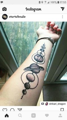 a person with a tattoo on their arm that has planets and stars in the middle