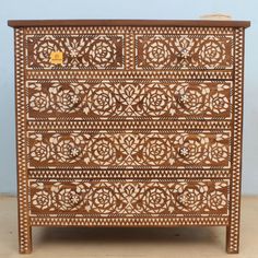 a wooden dresser with intricate carvings on the front and drawers, inlaid to wood