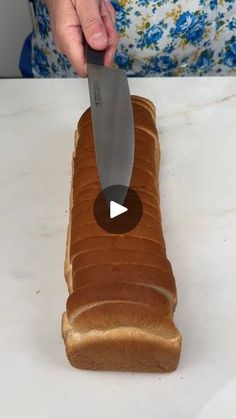 a person holding a knife over a loaf of bread