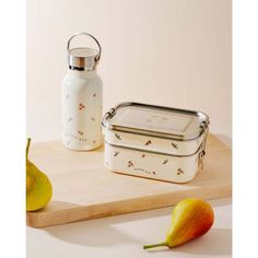 a white lunch box sitting on top of a wooden cutting board next to a pear