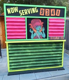 a sign that says now serving on the side of a building with an image of a woman