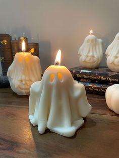 three white candles sitting on top of a wooden table next to books and candle holders