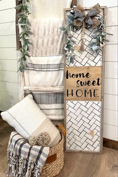 a wooden sign that says home sweet home next to some towels and blankets in a basket