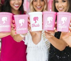 four beautiful women holding up pink cups with the names of their brides on them