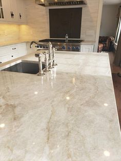 a kitchen counter top with two faucets on each side and an oven in the background