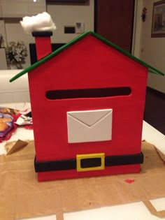 a red house with green roof and chimney on top of brown paper bags in front of a door