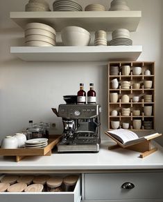 an espresso machine sitting on top of a counter next to plates and cups