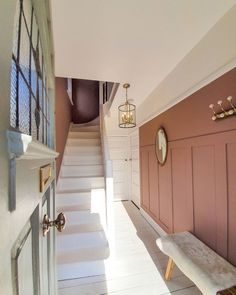 there is a white bench in the hallway next to some pink painted walls and stairs