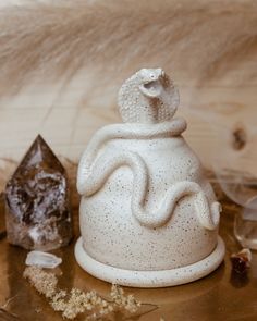 a white sculpture sitting on top of a wooden table next to crystals and other items