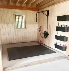 a room with wooden walls and flooring in the center is a black mat on the floor