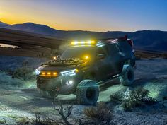 a truck with lights on driving through the desert