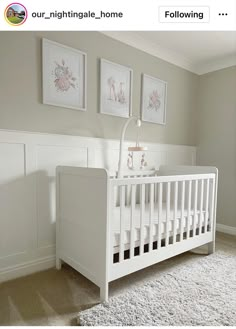 a white crib in the corner of a room with two pictures on the wall