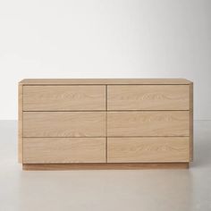 a large wooden dresser sitting on top of a white floor next to an empty wall