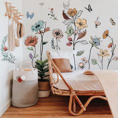 a bedroom with flowers painted on the wall and a wicker chair next to it