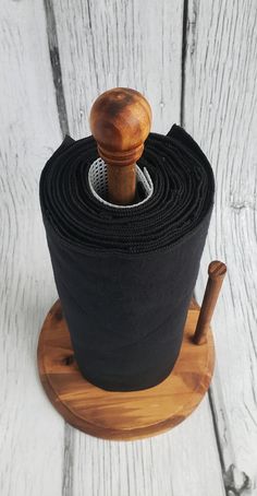 a roll of black yoga mat sitting on top of a wooden stand with a wooden handle