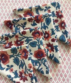 four pieces of cloth with red and blue flowers on them are sitting on a table