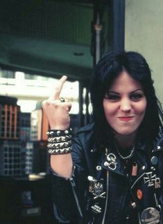 a woman with black hair and piercings giving the peace sign