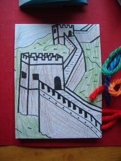 a drawing of a castle on a piece of paper next to some scissors and yarn